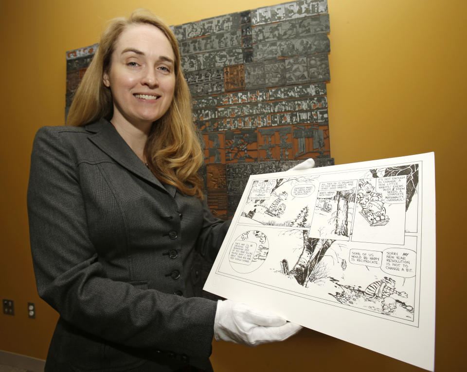 CORRECTS ID TO JENNY ROBB, NOT JULI SLEMMONS - In this Wednesday, Oct. 23, 2013 photo, Jenny Robb holds a "Calvin and Hobbes" comic by cartoonist Bill Watterson at the Billy Ireland Cartoon Library & Museum in Columbus, Ohio. Today the museum collection includes more than 300,000 original strips from everybody who’s anybody in the newspaper comics world, plus 45,000 books, 29,000 comic books and 2,400 boxes of manuscript material, correspondence and other personal papers from artists. (AP Photo/Tony Dejak)