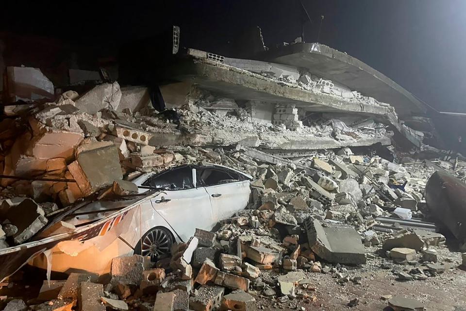 A car is seen under the wreckage of a collapsed building, in Azmarin town (Copyright 2023 The Associated Press. All rights reserved)