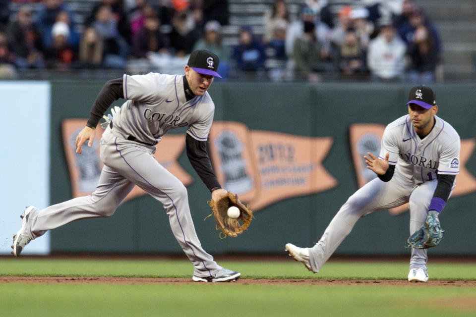 Colorado Rockies third baseman Ryan McMahon, left, cuts in front of shortstop José Iglesias, right, to field San Francisco Giants' Wilmer Flores' ground ball during the third inning of a baseball game, Monday, May 9, 2022, in San Francisco. Flores was out at first base. (AP Photo/D. Ross Cameron)