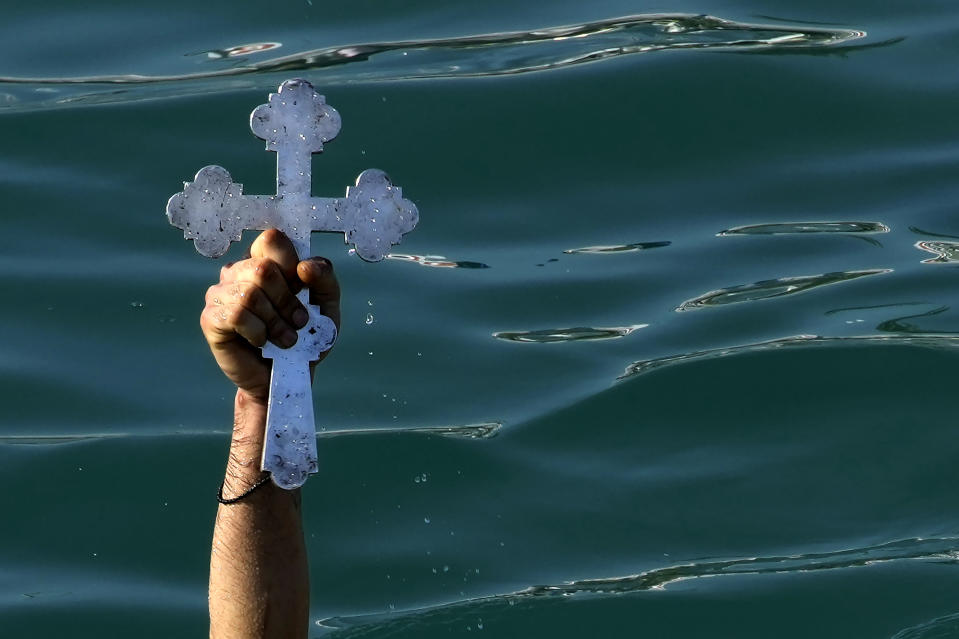 FILE - A pilgrim holds up the cross after it was thrown into the water by an Orthodox priest, during an Epiphany ceremony to bless the sea, on the southeast resort of Ayia Napa, Cyprus, Friday, Jan. 6, 2023. By tradition, a crucifix is cast into the waters of a lake or river, and it is believed that the person who retrieves it will be freed from evil spirits and will be healthy through the year. (AP Photo/Petros Karadjias, File)