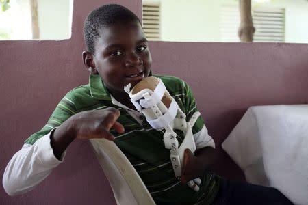 Handicapped Haitian boy Stevenson Joseph, holds the 3D-printed prosthetic hand that he is learning to use at the orphanage where he lives in Santo, near Port-au-Prince, May 5, 2014. REUTERS/Marie Arago