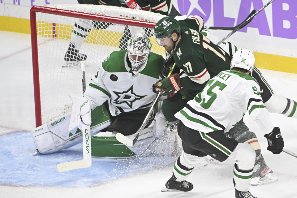 Dallas Stars goalie Jake Oettinger, left, blocks a shot by Minnesota Wild left wing Marcus Foligno, center, as Stars defenseman Thomas Harley, right, looks on during the first period of an NHL hockey game Sunday, Nov. 12, 2023, in St. Paul, Minn. (AP Photo/Craig Lassig)