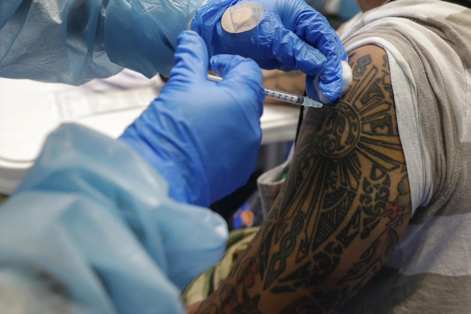 A health worker inoculates a man with tattoos with China's Sinovac COVID-19 vaccine inside the Makati Coliseum, Metro Manila, Philippines on Tuesday, May 4, 2021. The Philippines started a simultaneous vaccination of the initial 15,000 doses of Russia's Sputnik V COVID-19 vaccines that arrived in the country earlier this week. (AP Photo/Aaron Favila)