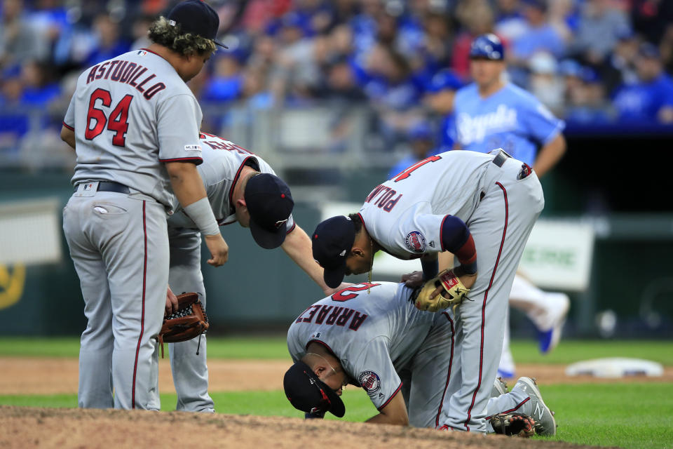 Minnesota Twins third baseman Luis Arraez (2) is checked on by teammates Willians Astudillo (64), Jorge Polanco (11) and Tyler Duffey, back, during the eighth inning of a baseball game against the Kansas City Royals at Kauffman Stadium in Kansas City, Mo., Saturday, Sept. 28, 2019. (AP Photo/Orlin Wagner)