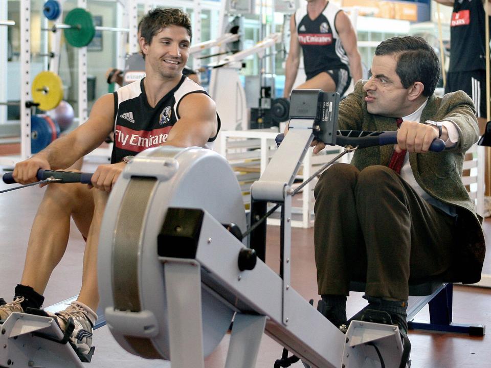 Actor Rowan Atkinson in character as Mr Bean trains on a rowing machine as Brodie Holland of the Magpies looks on during the Collingwood Magpies AFL gym training session at the Lexus Centre on March 9, 2007 in Melbourne, Australia.Getty Images