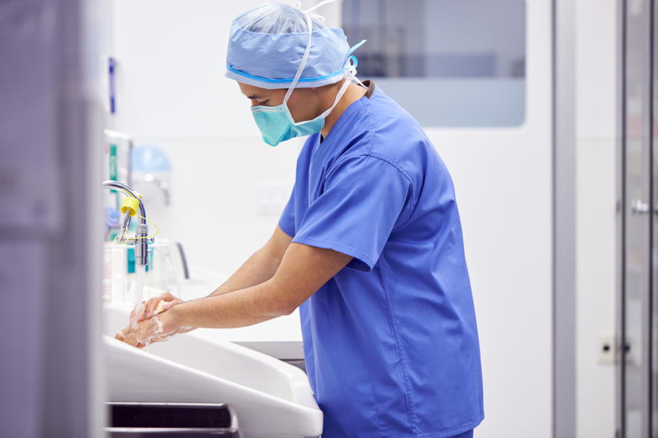 Male Surgeon Wearing Scrubs Washing Hands Before Operation In Hospital Operating Theater