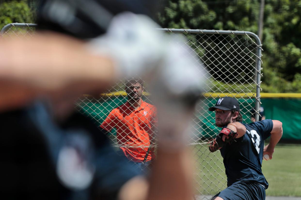 A coach looks on as Miami of Ohio University pitcher, Jonathan Brand, throws during the Wareham Gatemen first practice session in preparation for the upcoming Cape Cod Baseball League season.