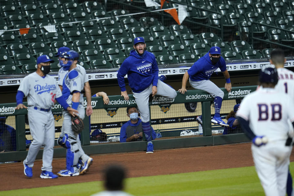 Los Angeles Dodgers' Clayton Kershaw, center, comes over the dugout railing along with other players during an exchange with Houston Astros' Carlos Correa (1) after the sixth inning of a baseball game Tuesday, July 28, 2020, in Houston. Both benches emptied onto the field during the exchange. (AP Photo/David J. Phillip)