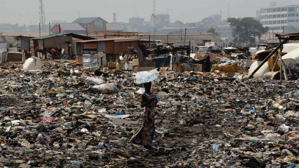 Eine Frau steht auf der Freifläche hinter dem Schrottplatz von Agbogbloshie in Ghana.