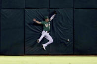 Oakland Athletics' Mark Canha crashes into the outfield wall on a triple hit by Seattle Mariners' Dylan Moore during the fourth inning of a baseball game in Oakland, Calif., Tuesday, Sept. 21, 2021. (AP Photo/Jed Jacobsohn)