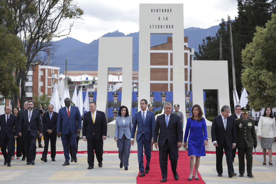 Colombia's President Ivan Duque, center of red carpet, US State Secretary Mike Pompeo, third person left of Duque, and Venezuela's opposition leader Juan Guaido, left on red carpet, walk after attending a ceremony marking one year since a car bomb attack at the police academy in Bogota, Colombia, during the inauguration of a regional anti-terrorism summit, Monday, Jan. 20, 2020. The Colombian government blamed rebels of the National Liberation Army, ELN, for the bombing that killed at least 21 people on Jan. 17, 2019. (AP Photo/Ivan Valencia)