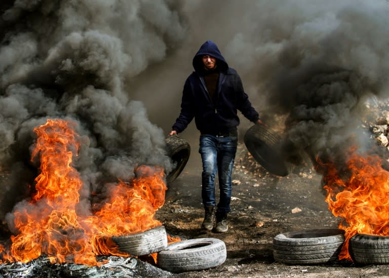 A Palestinian protester burns car tyres during clashes with Israeli security forces near Nablus, in the occupied West Bank, on January 13, 2017