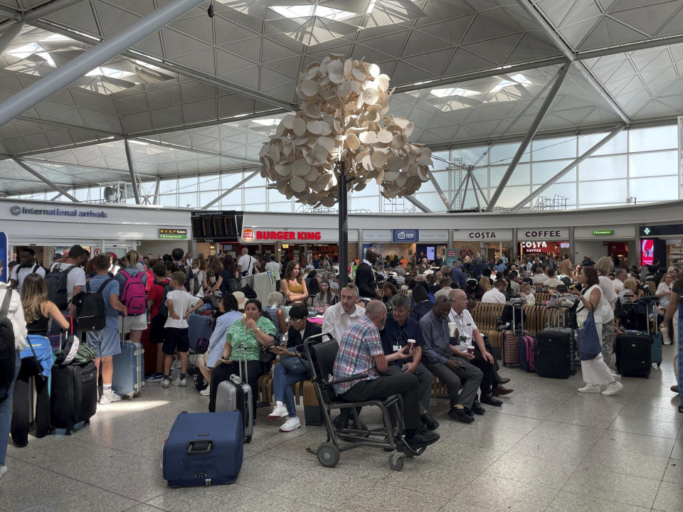 Passengers wait at London Stansted Airport in Essex, amid reports of widespread IT outages affecting airlines, broadcasters and banks, Friday July 19, 2024. (Joe Giddens/PA via AP)