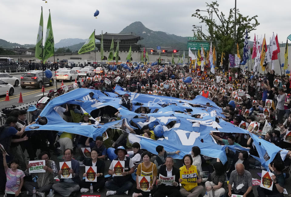 Protesters tear apart a flag symbolizing IAEA (International Atomic Energy Agency) during a rally against the Japanese government's decision to release treated radioactive water from the damaged Fukushima nuclear power plant, in Seoul, South Korea, Saturday, July 8, 2023. (AP Photo/Ahn Young-joon)