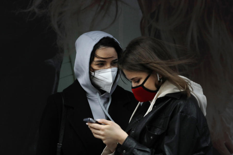 Women wearing masks talk in New York's Times Square, Thursday, April 9, 2020, during the coronavirus epidemic. The New York City immortalized in song and scene has been swapped out for the last few months with the virus version. In all the unknowing of what the future holds, there's faith in that other quintessential facet of New York City: that the city will adapt. (AP Photo/Mark Lennihan)