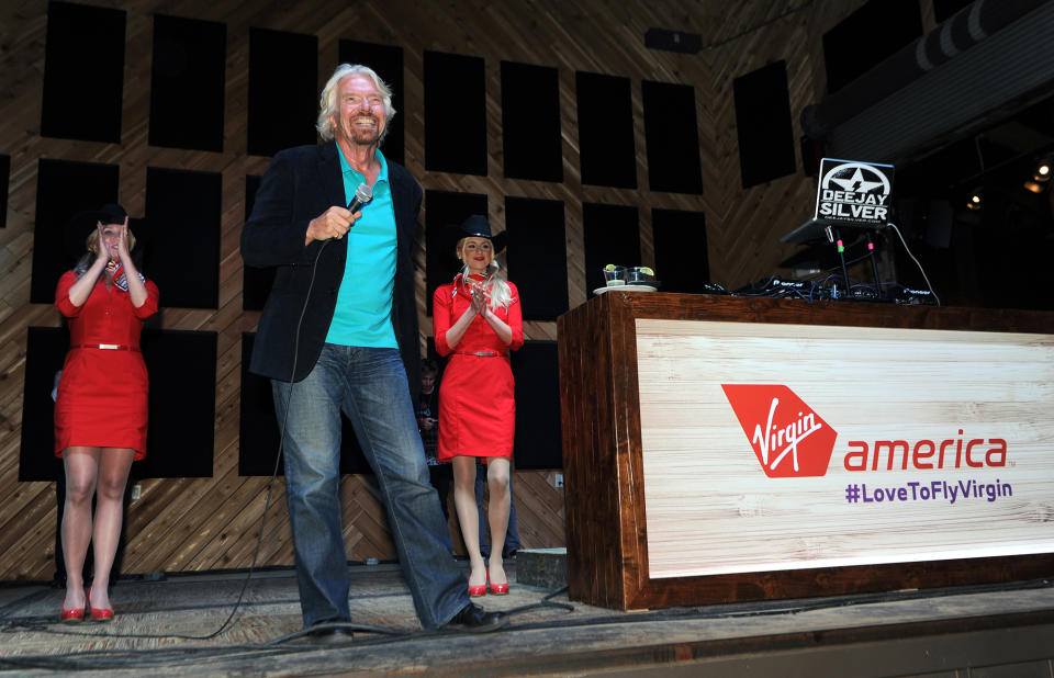 In this Monday, May 5, 2014 photo released by Virgin America Airlines, Virgin Group Founder Sir Richard Branson is joined by Virgin America teammates during an informal "Virgin-style rally' with local friends, city leaders and teammates to build support to secure two gates at Love Field, near downtown Dallas. Branson said Tuesday that Virgin should get the gates at Love Field to create competition for Southwest Airlines, which controls most of the gates there. The U.S. Justice Department agrees. (AP Photo/Virgin America, Bob Riha, Jr.)