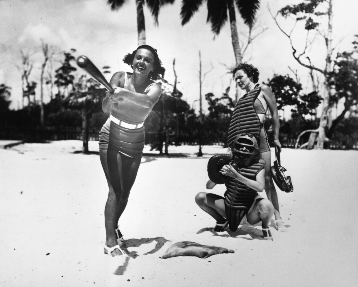 Young women playing a game of baseball on a beach in Miami, Florida.