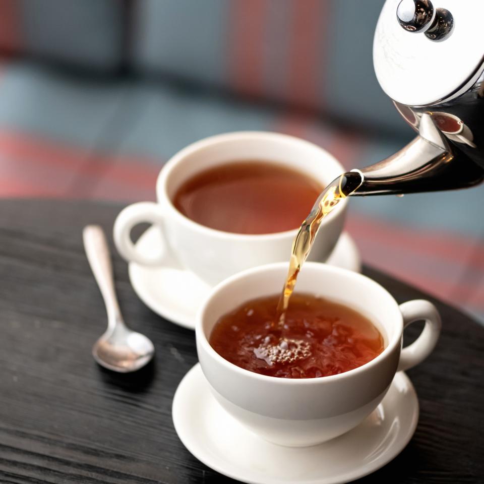 Two teacups with tea pouring into one