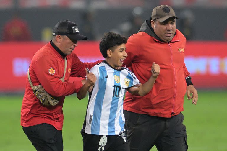 Un chico con la camiseta argentina es sacado de la cancha por personal de seguridad luego de haber invadido el terreno de juego; se llevó una foto con Messi