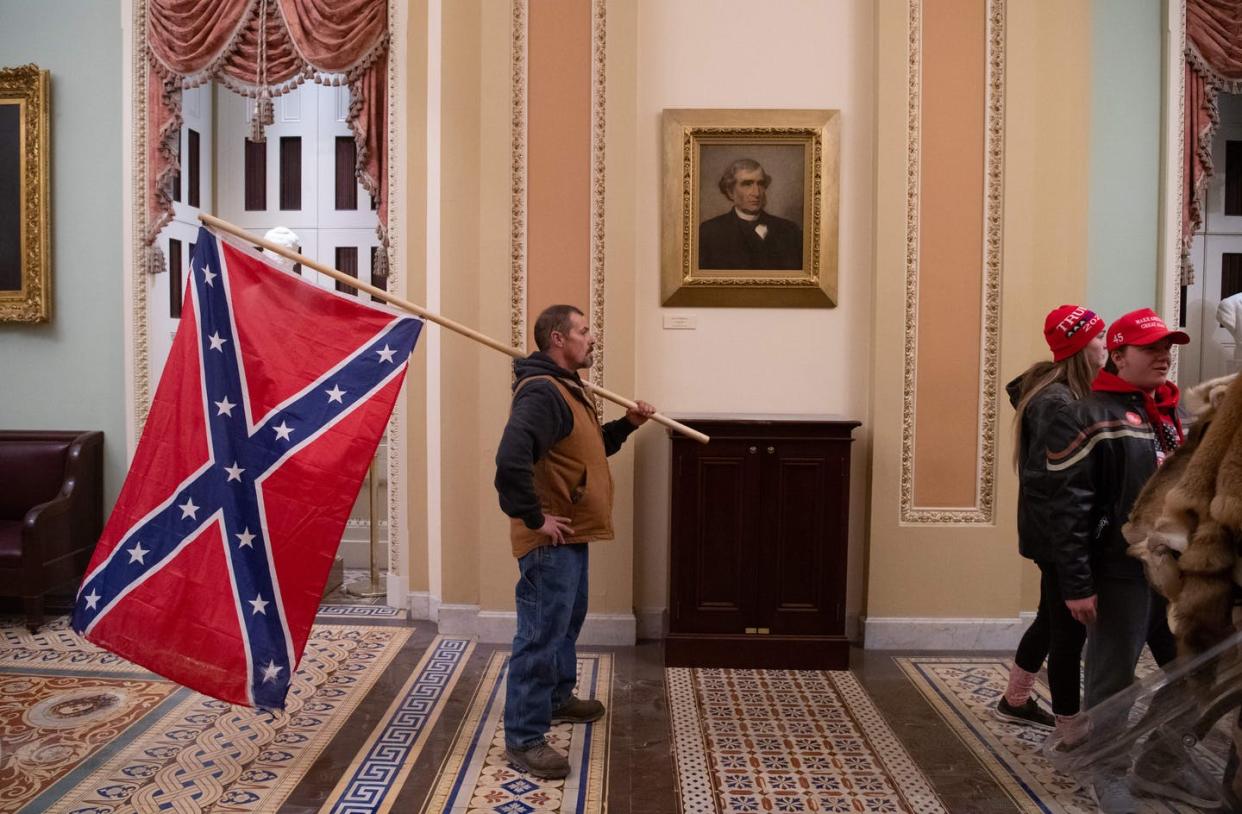 <span class="caption">A historic first: the Confederate battle flag inside the U.S. Capitol.</span> <span class="attribution"><a class="link " href="https://www.gettyimages.com/detail/news-photo/supporter-of-us-president-donald-trump-holds-a-confederate-news-photo/1230505137" rel="nofollow noopener" target="_blank" data-ylk="slk:Saul Loeb/AFP via Getty Images;elm:context_link;itc:0;sec:content-canvas">Saul Loeb/AFP via Getty Images</a></span>