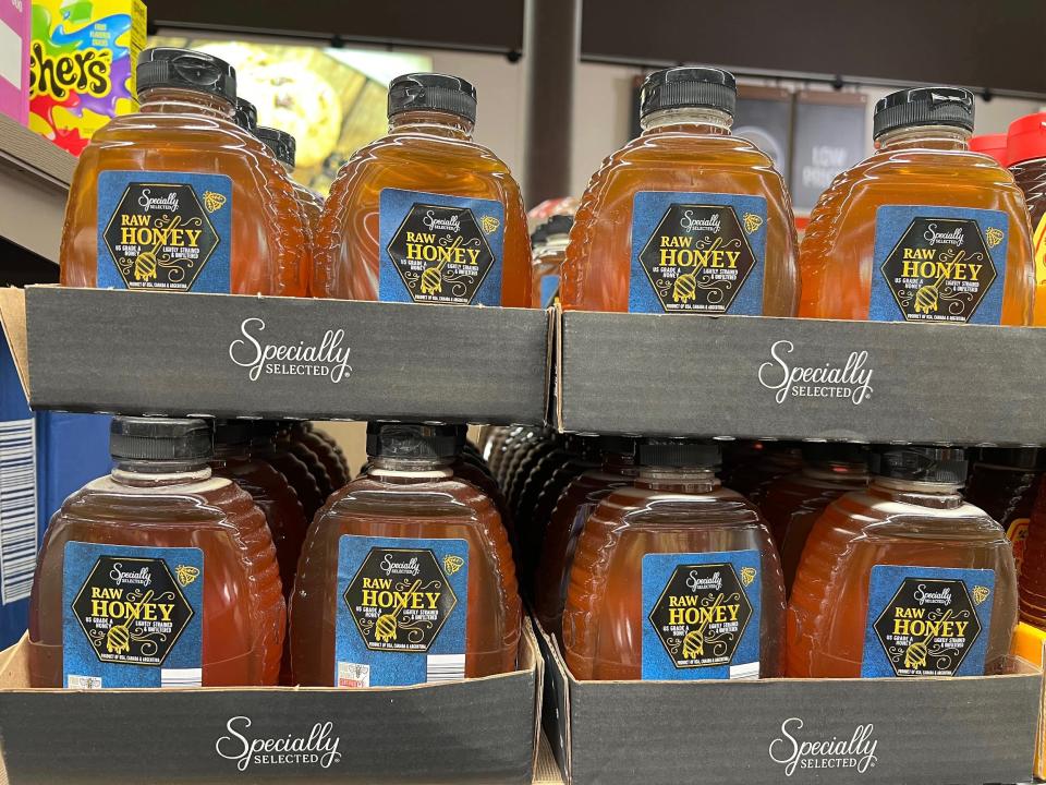 Jars of Specially Selected raw honey with black caps and blue labels at Aldi