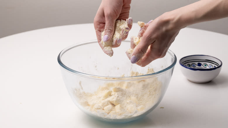 hands rubbing butter and flour shortbread dough over bowl