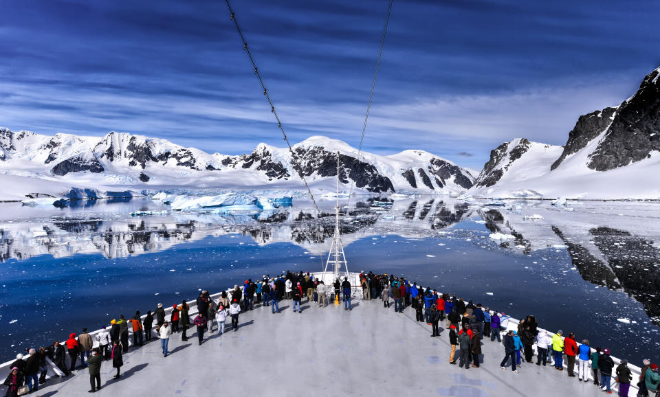 Pasajeros en la proa de un gran crucero de pasajeros a lo largo de la costa de la Antártida. Foto: Getty Images. 