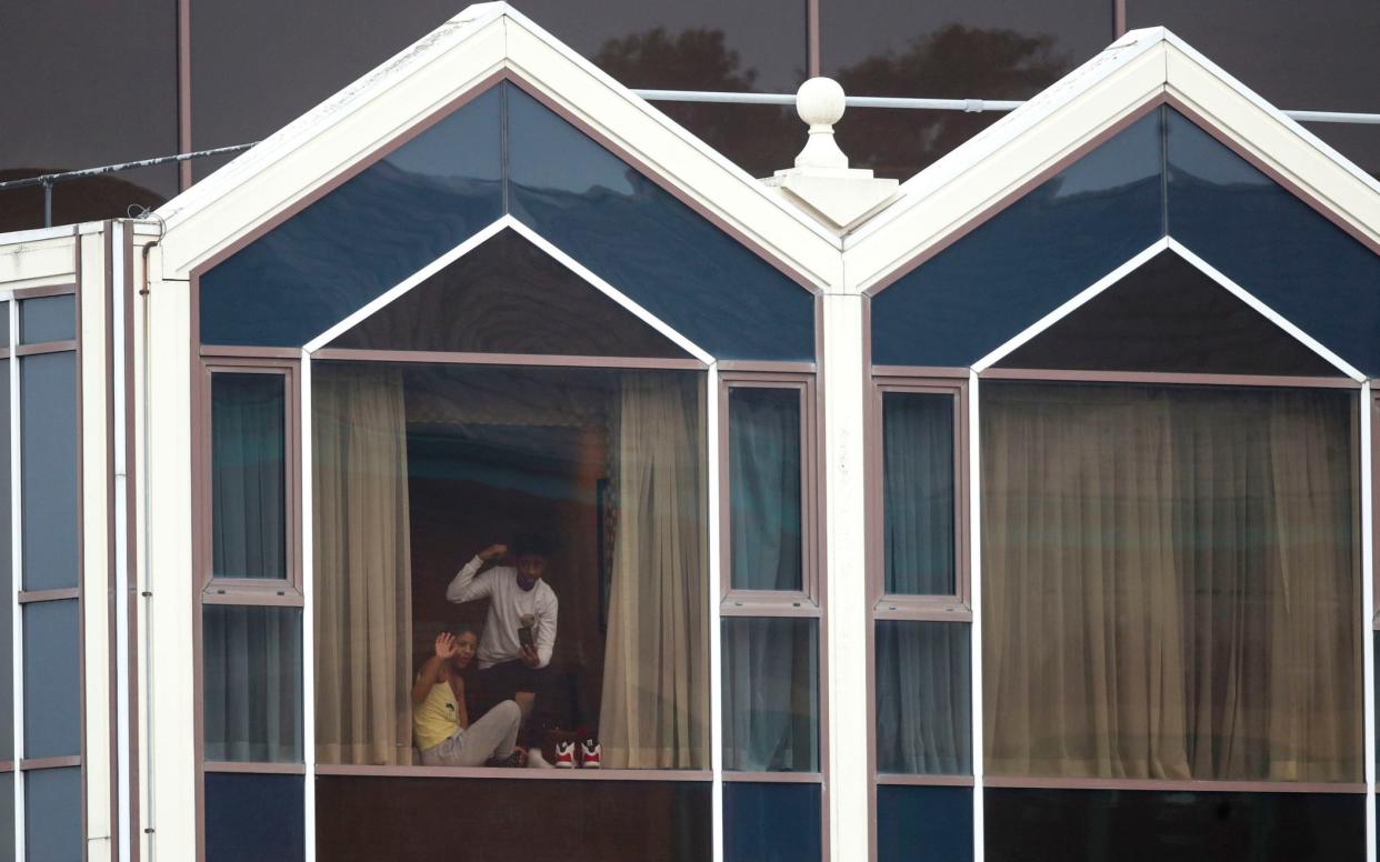 Guests look out of a window at the Radisson Blu hotel near Heathrow Airport during their 10-day quarantine - Steve Parsons/PA