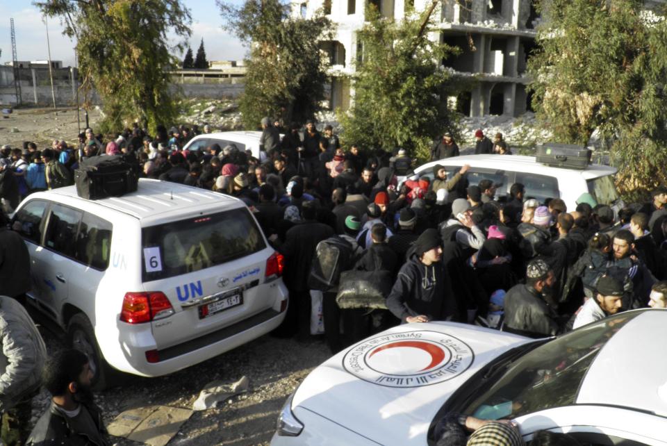 Civilians gather around vehicles belonging to the United Nations and Syrian Arab Red Crescent as they wait to be evacuated from a besieged area of Homs February 10, 2014. A second round of Syria peace talks got off to a shaky start on Monday, with the two sides complaining about violations of a local ceasefire and an Islamist offensive respectively in separate meetings with the international mediator. During the first round of talks in nearly three years of civil war last month, mediator Lakhdar Brahimi had tried to break down mistrust by focusing on agreeing a truce for a single city, Homs. REUTERS/Thaer Al Khalidiya (SYRIA - Tags: POLITICS CIVIL UNREST CONFLICT MILITARY)