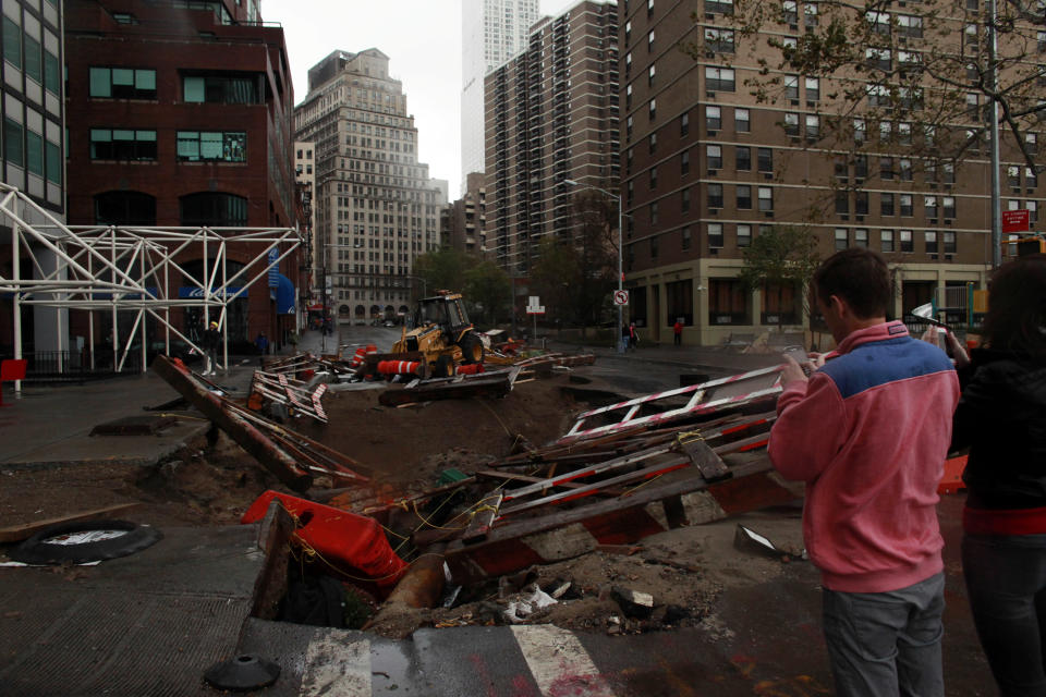 People stand by a hole that has formed at a construction site on South Street Seaport in Manhattan, New York. (Getty Images/Allison Joyce/Getty Images)