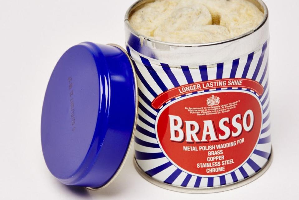 Opened can of Brasso with blue lid propped against the can.