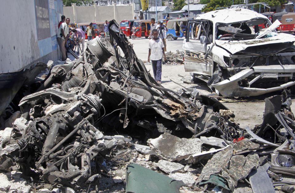 Somalis walk near the wreckage after a suicide car bomb attack in the capital Mogadishu, Somalia Wednesday, May 22, 2019. A police spokesman said the attack killed at least six people and injured more than a dozen, while Islamic extremist group al-Shabab claimed responsibility for the blast, saying it targeted vehicles carrying government officials. (AP Photo/Farah Abdi Warsameh)