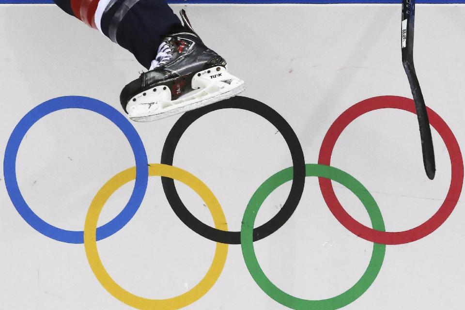 A USA women's ice hockey player jumps over the boards and into bench during third period of the game against Finland at the 2014 Winter Olympics womens ice hockey match at Shayba Arena, Saturday, Feb. 8, 2014, in Sochi, Russia. (AP Photo/J. David Ake)