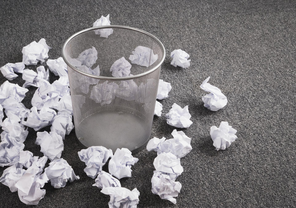 Discarded paper on floor around wastebasket