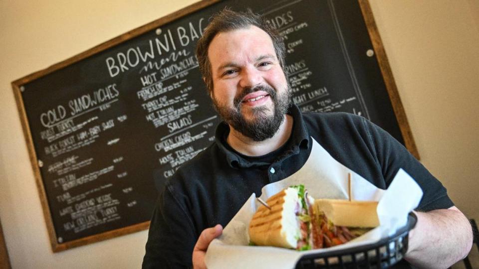 Chris Dias holds a hot Italian sandwich at his new sandwich shop, BrownBag, which opened next to the U.S. Citizen & Immigration field office on P Street in downtown Fresno, on Tuesday, Sept. 5, 2023.