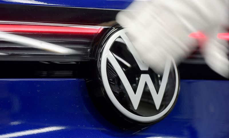 FILE PHOTO: A technician cleans a Volkswagen logo at the production line for electric car models of the Volkswagen Group, in Zwickau