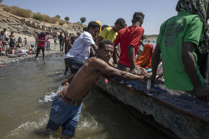 Tigray refugees who fled the conflict in the Ethiopia's Tigray ride a boat on the banks of the Tekeze River on the Sudan-Ethiopia border, in Hamdayet, eastern Sudan, Saturday, Nov. 21, 2020. The U.N. refugee agency says Ethiopia's growing conflict has resulted in thousands fleeing from the Tigray region into Sudan as fighting spilled beyond Ethiopia's borders and threatened to inflame the Horn of Africa region. (AP Photo/Nariman El-Mofty)