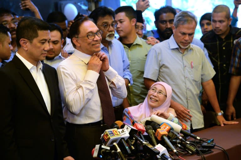 Anwar removes his tie before speaking to the media as his wife Wan Azizah (bottom R) looks on