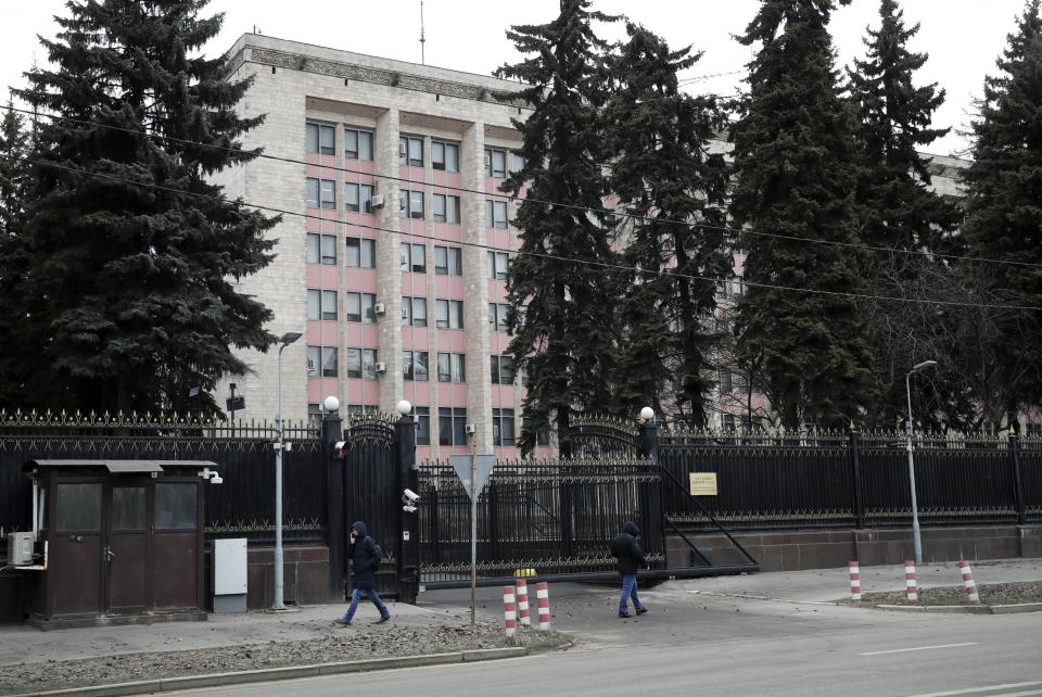 People walk past the building of the Chinese Embassy in Moscow, Russia, Friday, March 20, 2020. According to court filings and Russian defense lawyer Sergei Malik, authorities in Moscow are detaining and deporting some Chinese nationals for violating quarantine procedures the city government mandated in response to the coronavirus. For most people the coronavirus causes mild or moderate symptoms, but for some it can cause severe illness.(AP Photo/Pavel Golovkin)