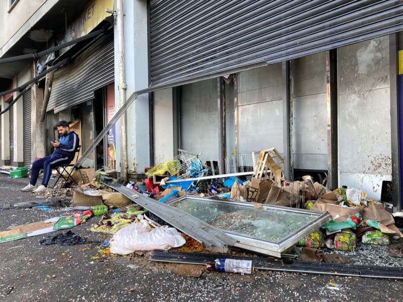 Abdelkader Mohamad Al Alloush, owner of the Sham Supermarket sits outsude his destroyed shop on Donegall Road in Belfast. The shop was burned during disorder in the area following an anti-immigration protest on Saturday. Another attempt was made to burn it during the disorder on Monday night. Rebecca Black/PA Wire/dpa