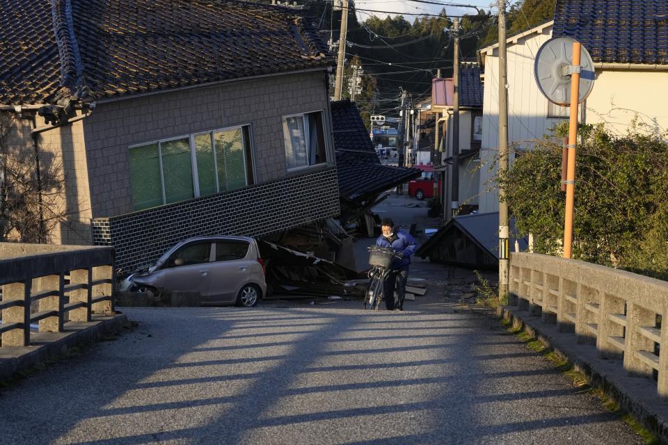 A person advances near some collapsed houses damaged by powerful earthquake in Anamizu in the Noto peninsula facing the Sea of Japan, northwest of Tokyo, Thursday, Jan. 4, 2024. More soldiers have been ordered to bolster the rescue operations Thursday, providing those in need with drinking water, hot meals and setting up bathing facilities after a magnitude 7.6 quake hit Ishikawa Prefecture and nearby regions Monday. (AP Photo/Hiro Komae)