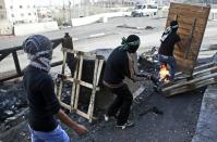 Palestinian demonstraters throw molotov cocktails towards Israeli security forces as they stand next to Israel's controversial separation wall