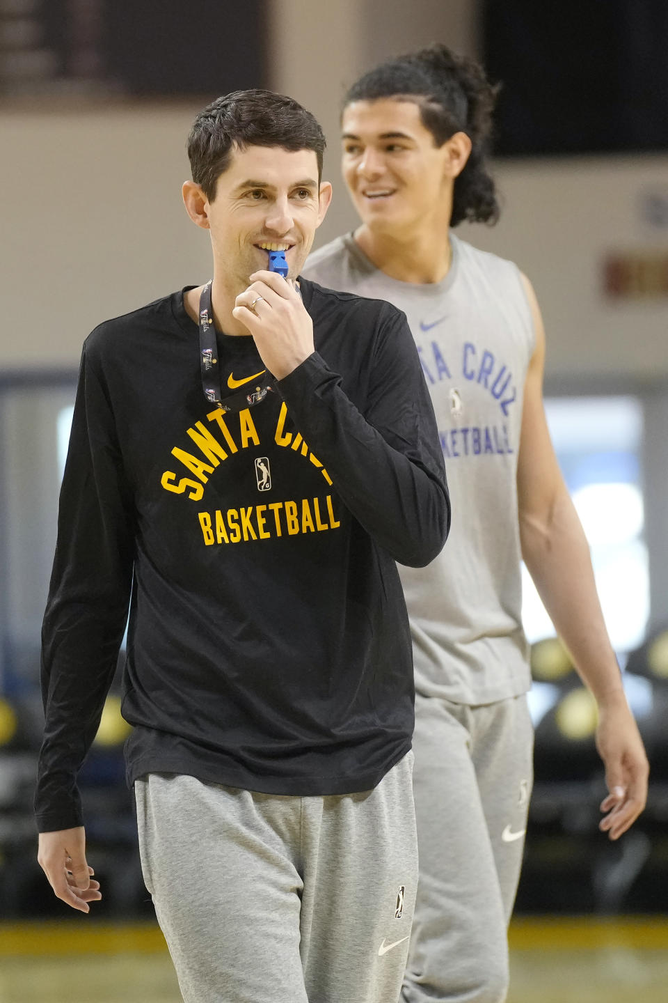 Santa Cruz Warriors coach Nicholas Kerr, foreground, walks on the court in front of forward Gui Santos during the team's basketball practice in Santa Cruz, Calif., Friday, Jan. 12, 2024. Each day, Kerr strives to find a balance between fun and fire while leading Golden State's developmental G League team minus all the big stars - like Stephen Curry - his famous father, Steve Kerr, gets to work with every day. (AP Photo/Jeff Chiu)