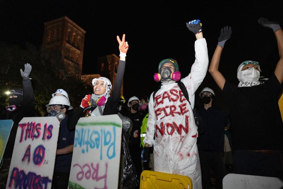 Demonstrators stand and raise their arms.