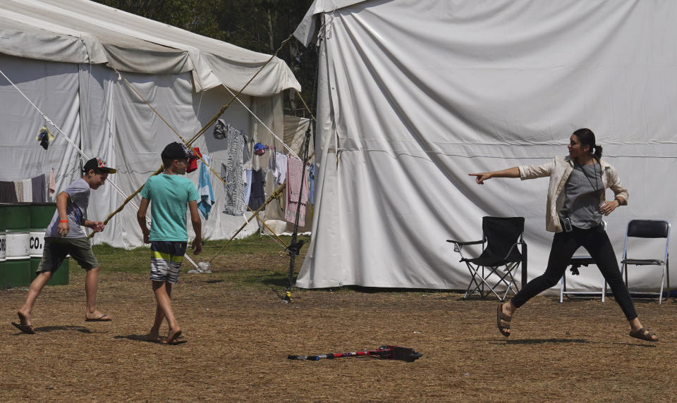 A young Ukrainian woman warns boys in a water balloon fight to not throw a water balloon at her, at a camp in the Iztapalapa borough of Mexico City, Tuesday, May 24, 2022. Mexico City will close the camp that has hosted hundreds of Ukrainian refugees for the past month. Now that a U.S. program vetting refugees and then allowing them to fly to the U.S. is operational, authorities say the camp is no longer needed. (AP Photo/Marco Ugarte)