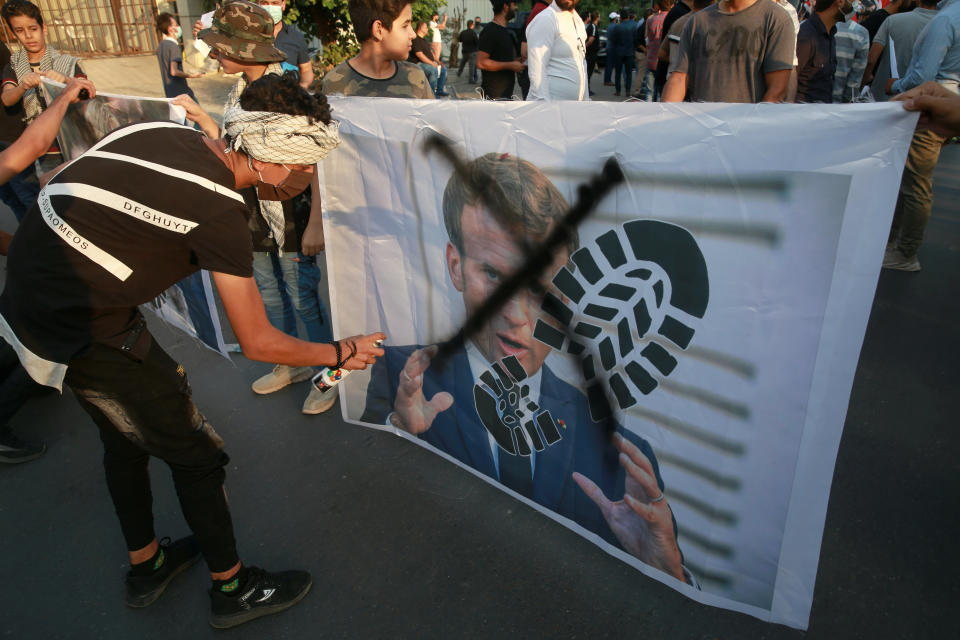 Manifestantes tachan una imagen del presidente francés Emmanuel Macron durante una protesta contra las caricaturas del profeta Mahoma, las cuales consideran blasfemas e insultantes, frente a la embajada de Francia en Bagdad, Irak, el lunes 26 de octubre de 2020. (AP Foto/Khalid Mohammed)