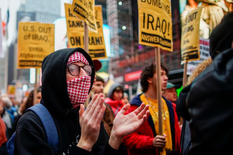 A man covers his face as people take part in an anti-war protest amid increased tensions between the United States and Iran at Times Square in New York