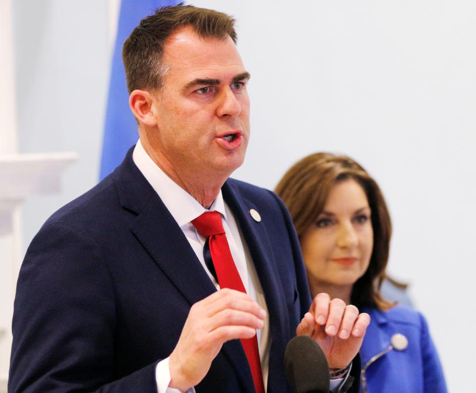 Gov. Kevin Stitt speaks at the state Capitol as Joy Hofmeister looks on.