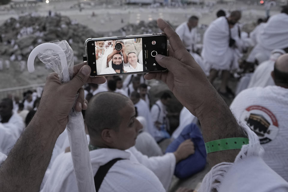 Pilgrims pose for a selfie at top of the rocky hill known as the Mountain of Mercy, on the Plain of Arafat, during the annual Hajj pilgrimage, near the holy city of Mecca, Saudi Arabia, Tuesday, June 27, 2023. Around two million pilgrims are converging on Saudi Arabia's holy city of Mecca for the largest Hajj since the coronavirus pandemic severely curtailed access to one of Islam's five pillars. (AP Photo/Amr Nabil)