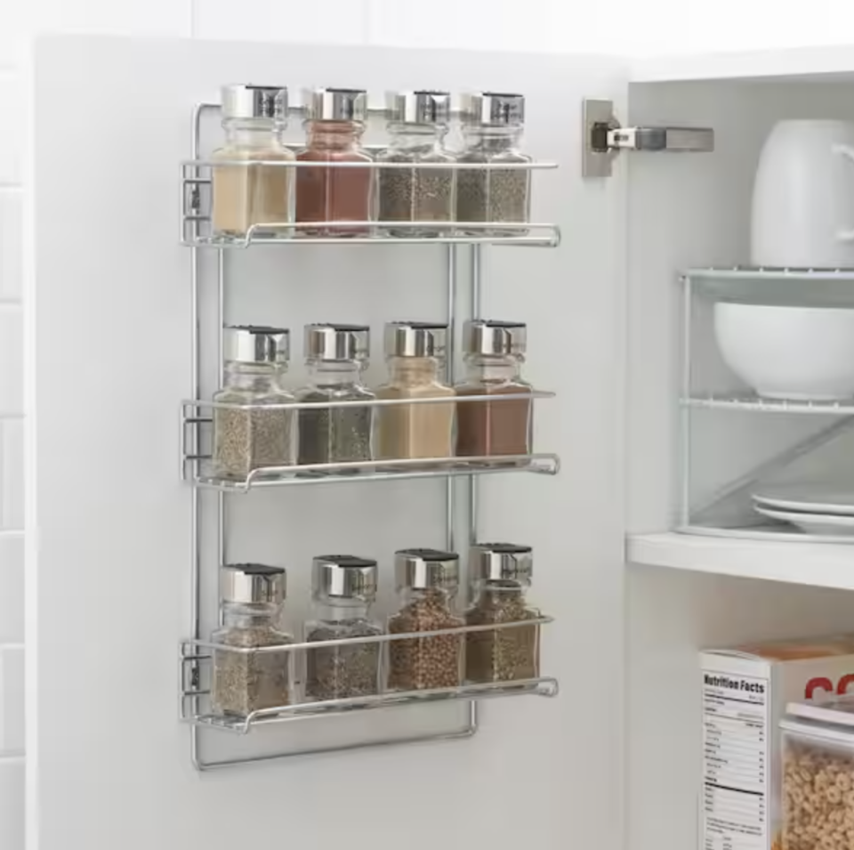 A spice rack mounted on the inside of a cabinet 